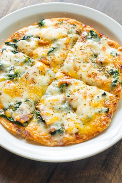 spinach and bacon pizza on white plate