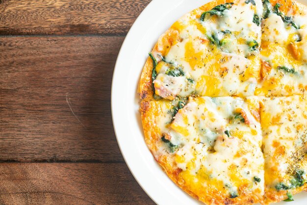 spinach and bacon pizza on white plate