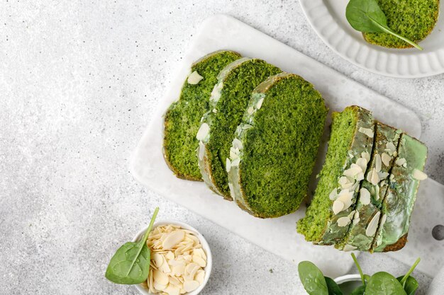 Torta di spinaci con mandorle a scaglie tagliate su tavola di marmo sfondo grigio vista dall'alto