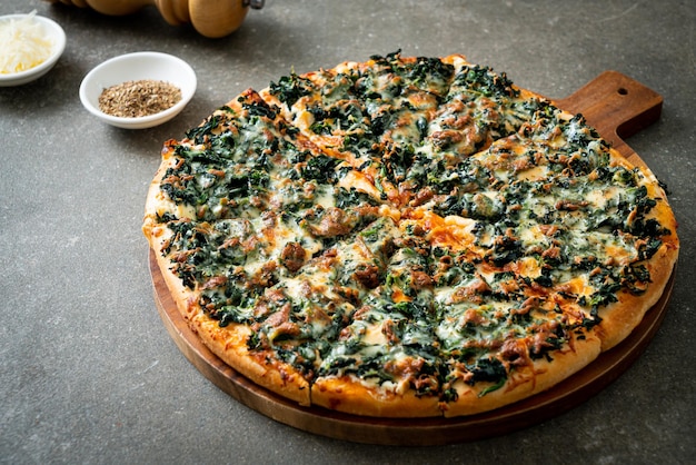Pizza con spinaci e formaggio su vassoio di legno - stile alimentare vegano e vegetariano