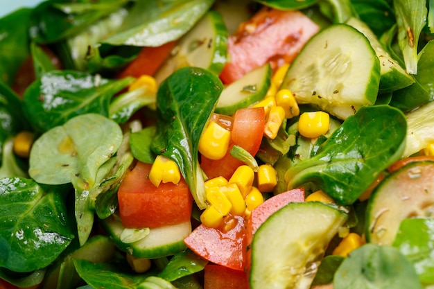 Spinach, corn, tomato and cucumber salad with olive oil. Food is proper nutrition. Vegetarian food