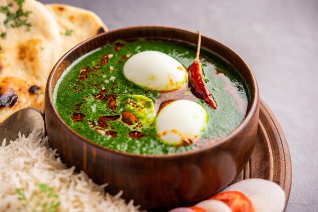 Photo spinach egg curry is an indian non vegetarian dish made using palak gravy with eggs