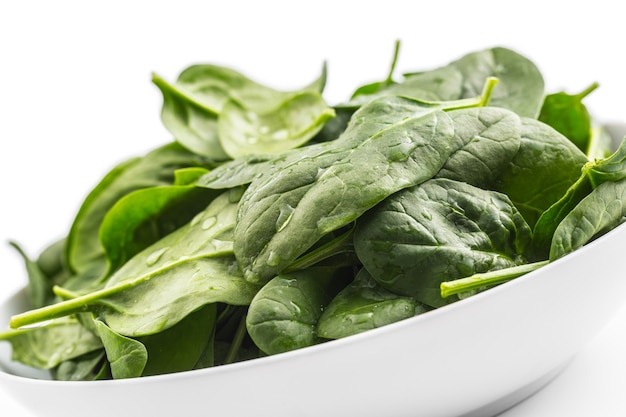 Spinach. Fresh baby spinach leaves in plate isolated on white.