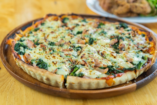 Spinach and goat cheese pizza on wooden table