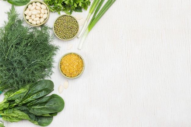 Spinach leaves, dill, green onions and mung bean, nuts and bulgur on table. White background. Copy space