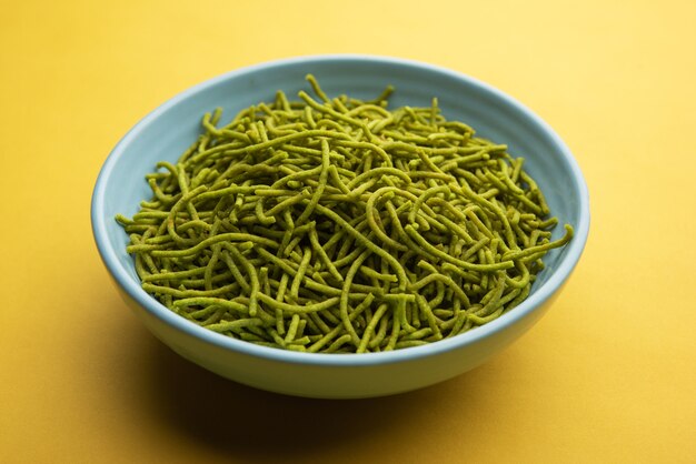 Spinach or palak sev are crunchy fried savory noodles. Homemade Thick and thin green shev or namkeen is a classic Indian snack. served in a bowl or plate