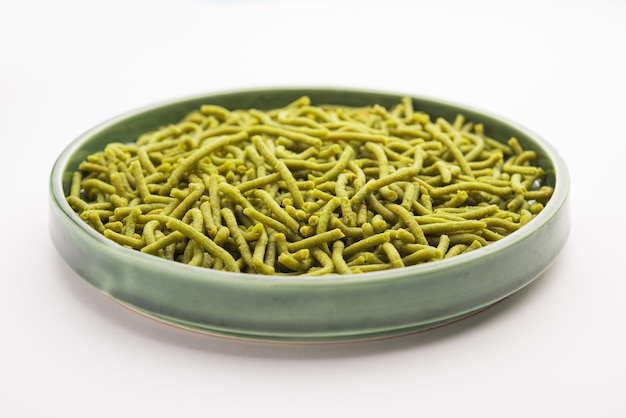 Spinach or palak sev are crunchy fried savory noodles. Homemade Thick and thin green shev or namkeen is a classic Indian snack. served in a bowl or plate