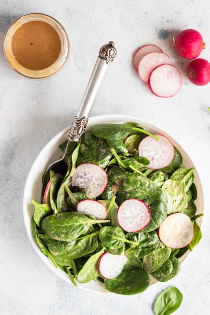 Spinach and radish salad with peanut butter dressing. Healthy vegetarian food. 