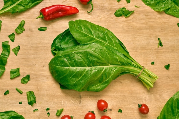 Spinach, red pepper, carrot ,onion, cherry tomatoes and green herbs on a wooden counter.