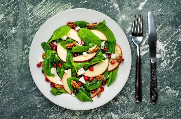 Spinach Salad, Apple, Pomegranate, Cheese, Walnut Salad on Concrete, Slate Background