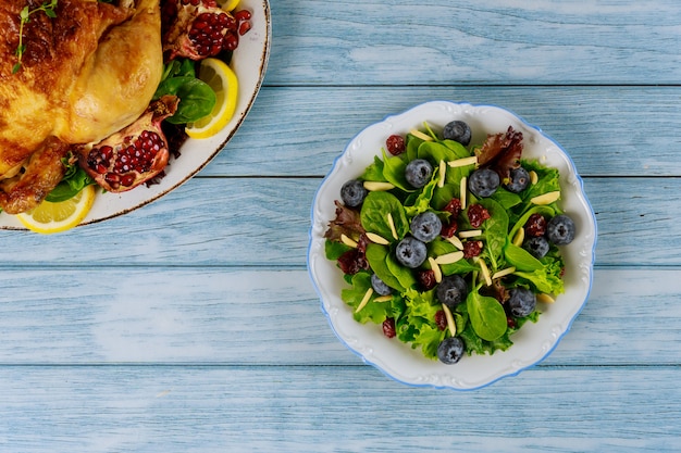 Spinach salad with cranberry, blueberry and slivered almond next to roasted chicken