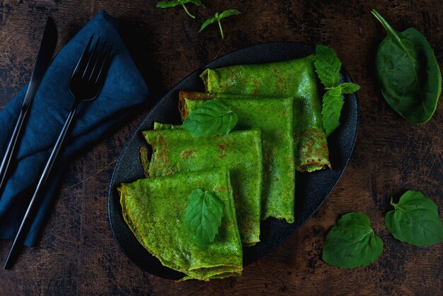 Spinach thin pancakes are green on a wooden table. Horizontal photo. Top view