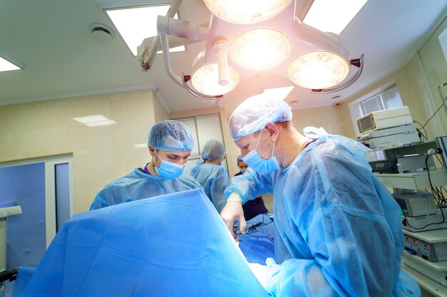 脊椎手術。手術装置を備えた手術室の外科医のグループ。画面を見ている医者。現代医学の背景