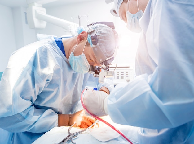 Spinal surgery. Group of surgeons in operating room with surgery equipment.