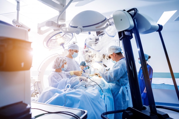 Spinal surgery. Group of surgeons in operating room with surgery equipment.