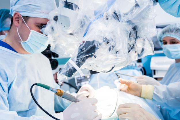 Spinal surgery. Group of surgeons in operating room with surgery equipment.