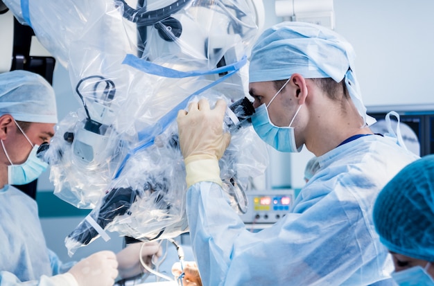 Spinal surgery. Group of surgeons in operating room with surgery equipment.