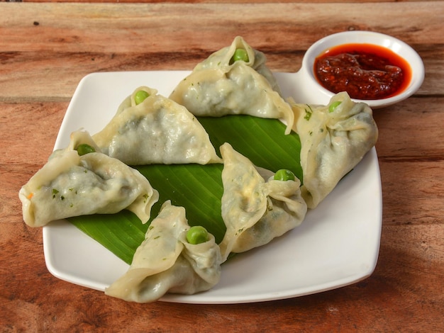 Spinazie en kaas momo Nepalese traditionele schotel Momo gevuld met spinazie kaas en vervolgens gekookt en geserveerd met saus op een rustieke houten achtergrond selectieve aandacht