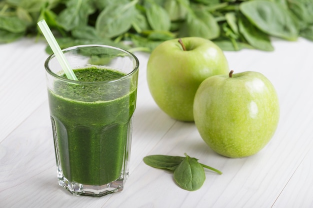 Spinazie met appelsap een frisdrankpot met stro op witte houten tafel