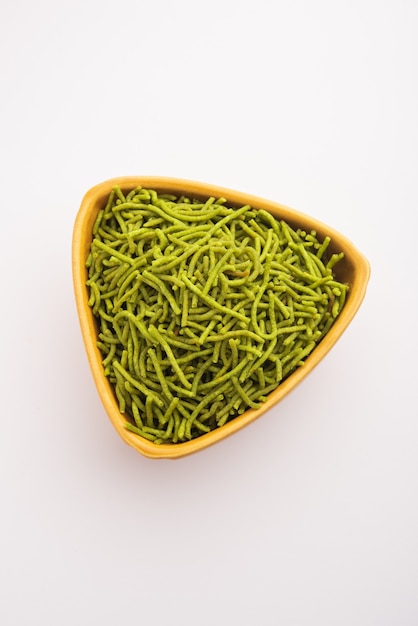 Spinazie of palak sev zijn krokant gebakken hartige noedels. Zelfgemaakte Dikke en dunne groene shev of namkeen is een klassieke Indiase snack. geserveerd in een kom of bord