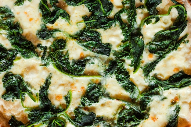 Spinazie pizza achtergrond. smakelijke en voedzame maaltijd voor vegetariërs. gezond eten veganistische levensstijl. moderne italiaanse keuken