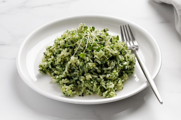 Spinazierijst met microgreens op wit bord met vork op marmeren Achtergrond Gezond vegetarisch dieet