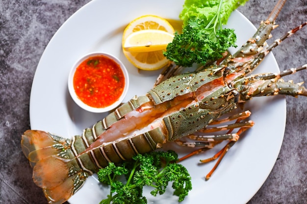 Spiny lobster sashimi seafood fresh lobster or rock lobster with herb and spices lemon parsley on dark background raw spiny lobster for cooking food
