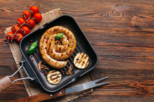 사진 나무 표면에 냄비에 야채 조각으로 나선 맛있는 구운 된 소시지