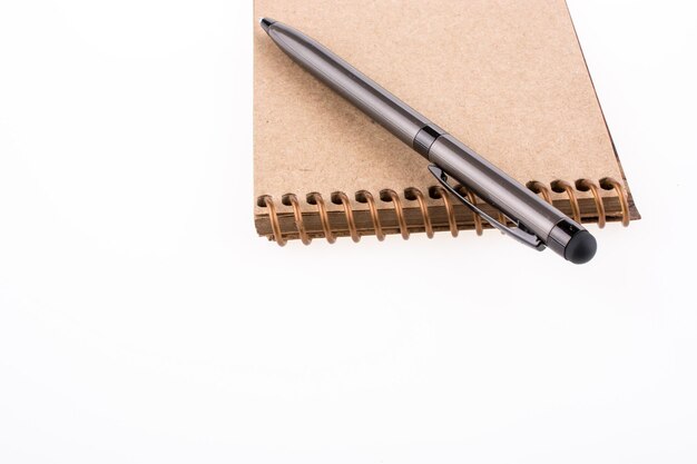 Spiral notebook and pollpoint pen on a white background