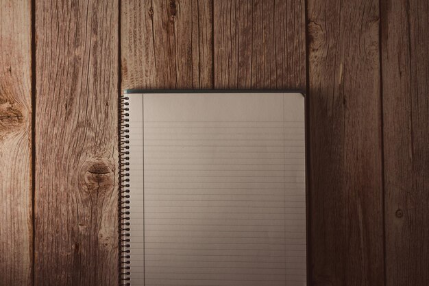 spiral notebook in white with lines on wooden background top view copy space selective focus
