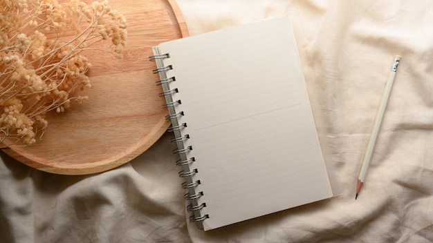 A spiral notebook with an empty cover page in a cozy minimal decorative workspace composition. above