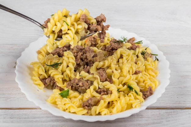 Spiralen pasta Bolognese Tagliatelle met gehakt op een witte plaat op een houten ondergrond