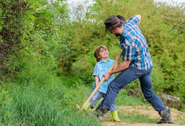 Spirit of adventures. Adventure hunting for treasures. Little helper in garden. Cute child in nature having fun cowboy dad. Find treasures. Little boy and father with shovel looking for treasures.