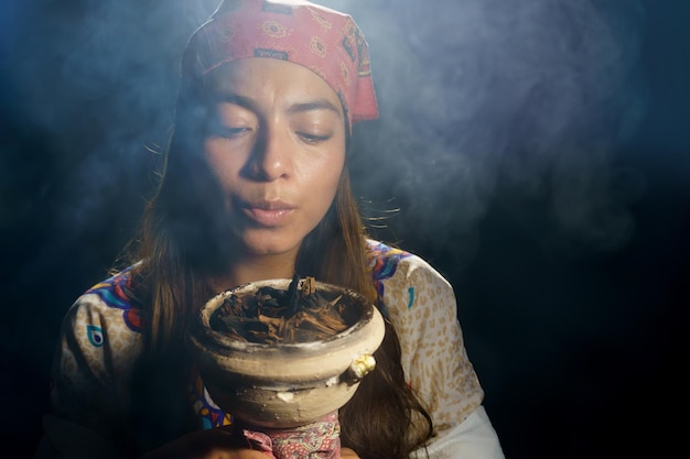 Foto una donna spirituale che tiene in mano tabacco e incenso bruciati