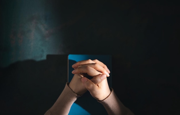 Spiritualiteit religie en hoop concept persoon bidden door Heilige Bijbel op Bureau symbool van nederigheid smeekbede geloof en geloof voor christelijke mensen bovenaanzicht