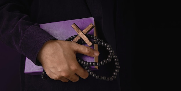 Photo spirituality religion and hope concept person holding a holy bible bead and cross symbol of humility supplication believe and faith for christian people dark tone closeup and side view