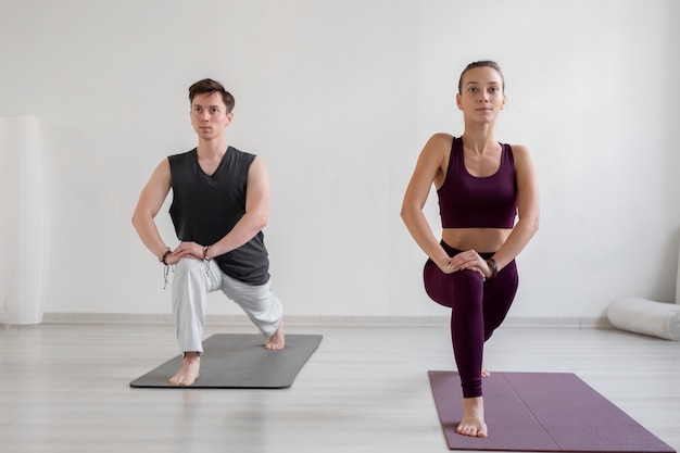 Spirituele jonge man en vrouw die binnen yoga beoefenen