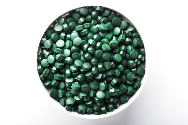 小さなつめの明るい背景の緑色の錠剤にスピルリナとクロレラの錠剤