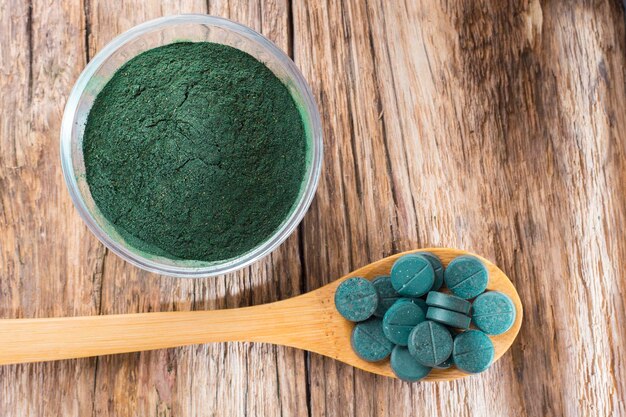 Spirulina-poeder en tabletten op houten ondergrond