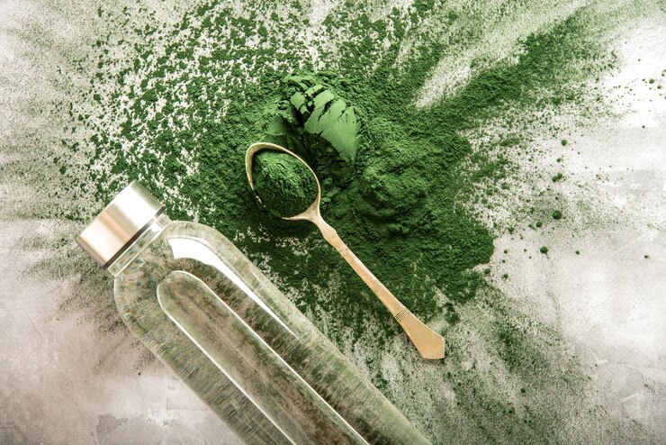 spirulina powder scattered on a concrete background with bottle of water