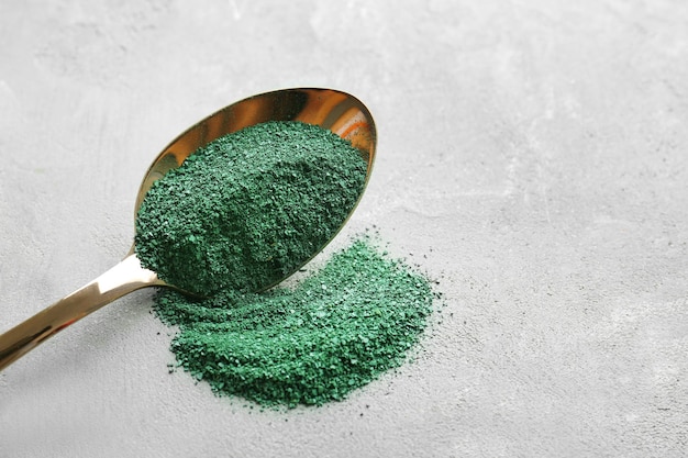 Spirulina powder in spoon on table