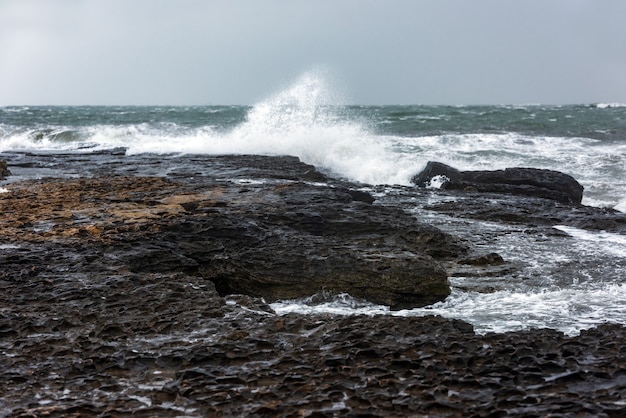 Foto spruzzata di grandi onde su un paesaggio roccioso in riva al mare