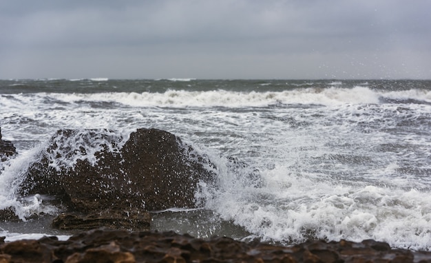 Splash of big waves on a rocky seashore landscape