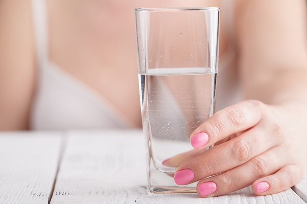 Всплеск чистой воды в стакане в женских руках
