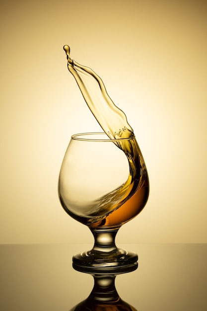 Splash of cognac in glass isolated on a light background