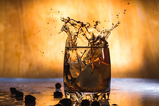 Splash of cold ice in glass of whiskey