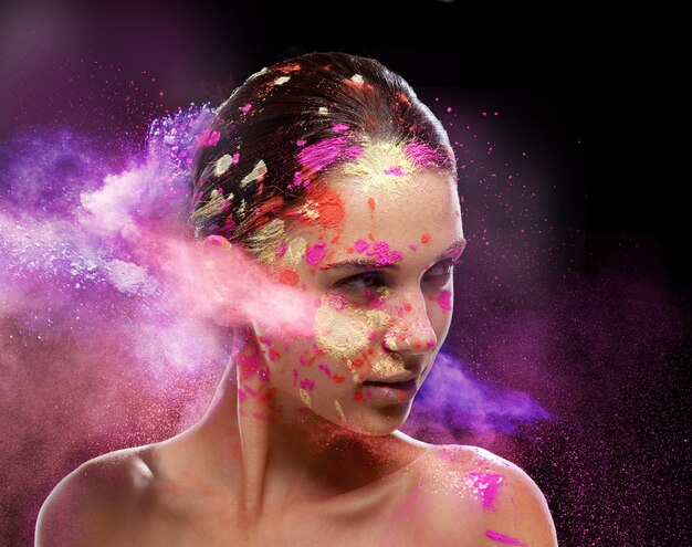 Splash of color Conceptual shot of a beautiful young woman covered in multicolored powder paint