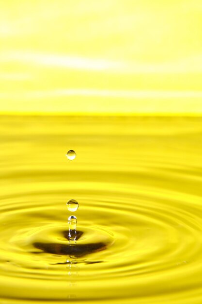 Photo splash drop of water with diverging water circles on yellow background