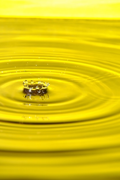 Photo splash drop of water with diverging water circles on yellow background