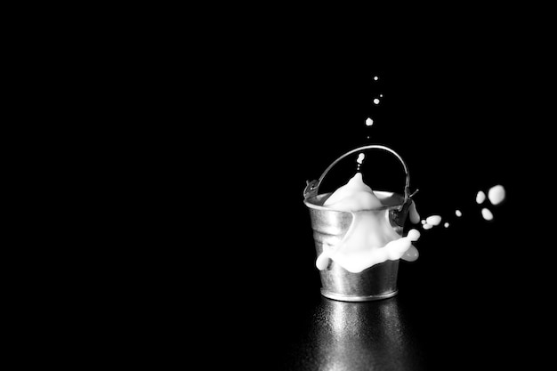 Splash in metal bucket with milk on black